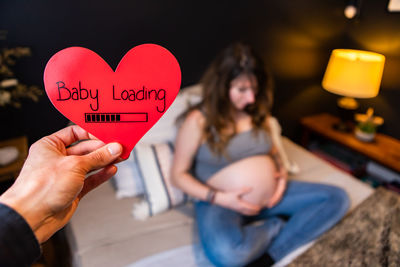 Midsection of woman holding heart shape with text