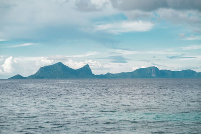 Scenic view of sea by mountains against sky