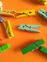 High angle view of colorful wooden clothespins on orange background