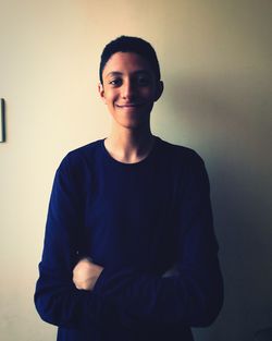 Portrait of smiling young man standing against wall