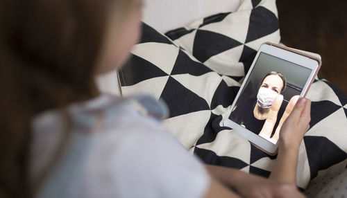 Girl using mobile phone on sofa at home