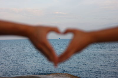 Close-up of heart shape over sea against sky