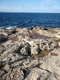 Scenic view of rocks on beach against sky