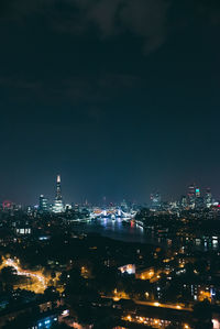 Illuminated cityscape by sea against sky at night