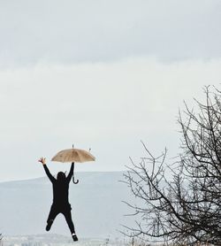 Woman holding umbrella against sky
