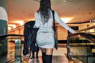 Rear view of woman on escalator in shopping mall