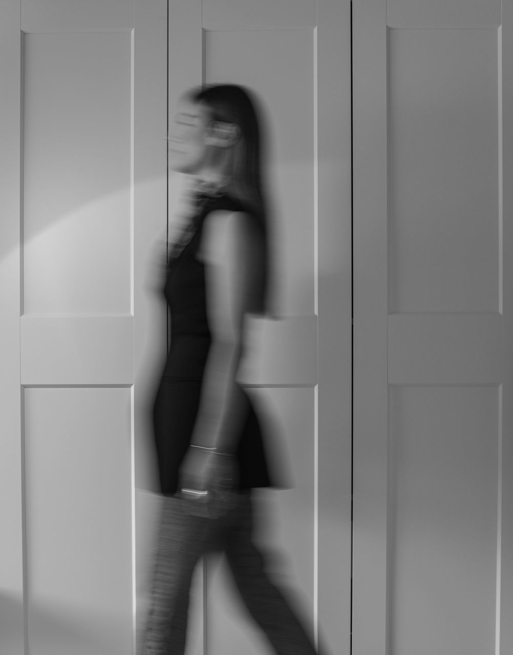 SIDE VIEW OF YOUNG WOMAN WALKING AGAINST WALL