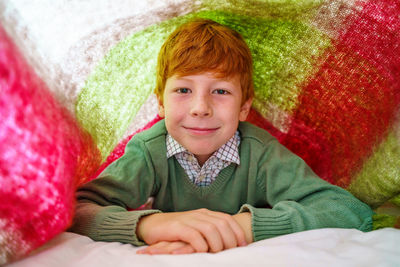 Portrait of smiling boy lying on bed