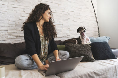 Young woman using laptop while sitting on sofa at home