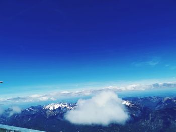 Aerial view of snowcapped mountains against blue sky