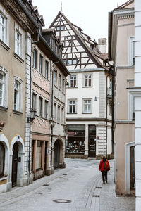 Man walking on footpath amidst buildings in city