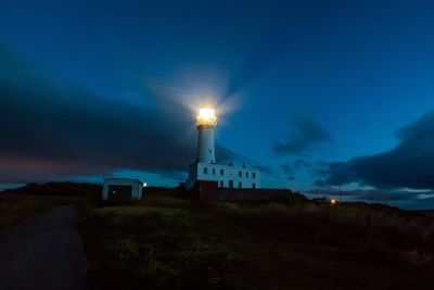 Lighthouse by sea against sky at night