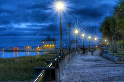 Illuminated street light against sky at night