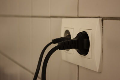 Close-up of black plugs in outlets on wall