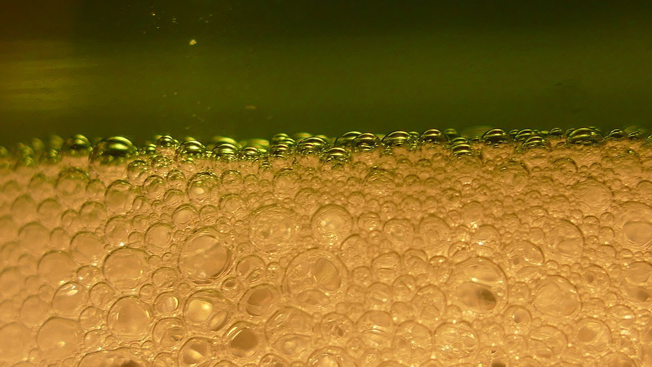 CLOSE-UP OF WATER DROPS ON GLASS AGAINST BACKGROUND