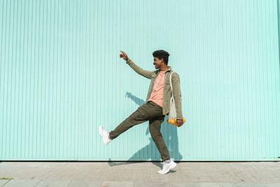 Young man with arms raised on wall