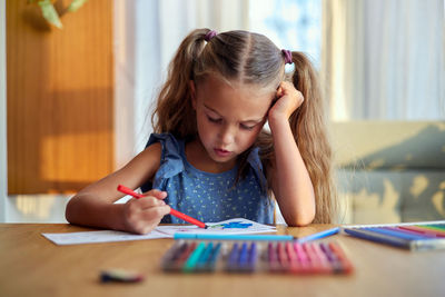 Concentrated girl painting with colorful pencils