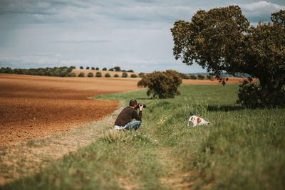 Man photographing dog on grassy field