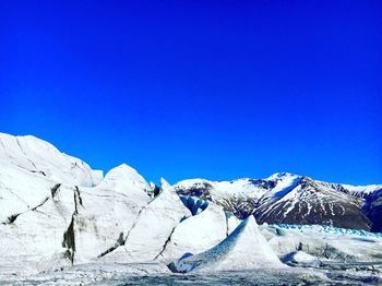 Scenic view of snowcapped mountains against clear blue sky