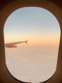 Airplane flying in sky seen through glass window