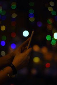 Close-up of hand holding illuminated smart phone at night