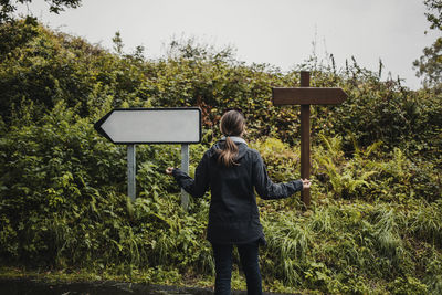 Rear view of woman standing against plants during rainy season