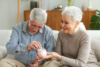 Portrait of smiling mother and daughter sitting on sofa at home