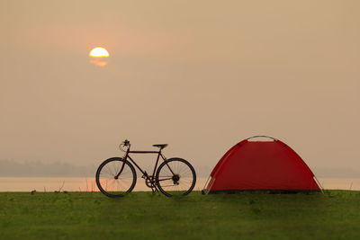 Bicycle on field against sky during sunset