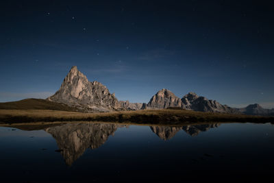 Scenic view of lake and mountains against sky at night