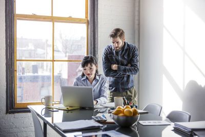 Business people looking at laptop while working in creative office