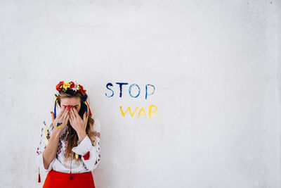 Portrait of young woman standing against wall