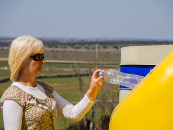 Midsection of woman holding sunglasses against clear sky