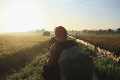 Rear view of man standing on field against sky