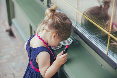 Portrait of young woman looking through window