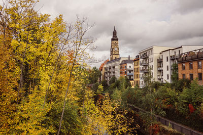 View of trees and buildings against cloudy sky