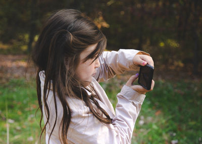 Close-up of cute girl photographing while standing in yard