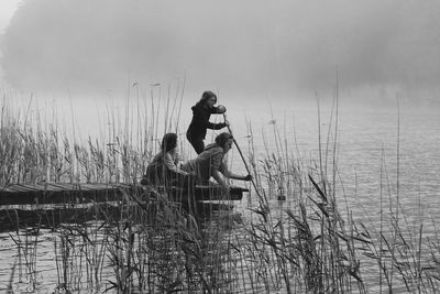 Mother with daughters on pier over lake during foggy weather