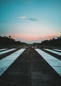 Surface level of footpath against sky during sunset