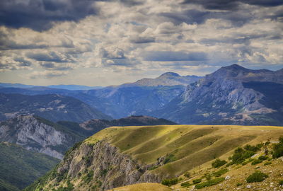 Wavy plateau with the cliff high in mountains and heavy rainy clouds in the sky. 