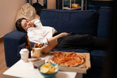 Full length of man sitting on table at home