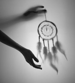 Cropped image of hand holding dreamcatcher indoors