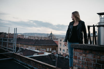 Young woman looking at cityscape against sky