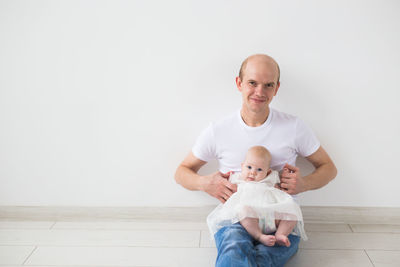 Portrait of a smiling girl holding baby on floor