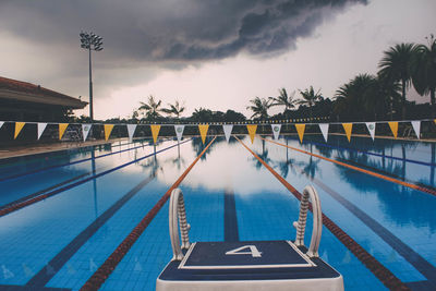 Swimming pool by trees against sky