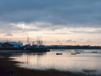 Boats at harbor against sky during sunset