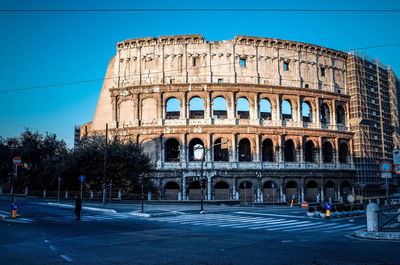 View of coliseum next to road against clear sky