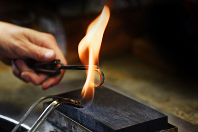 Cropped hand holding ring in fire at workshop