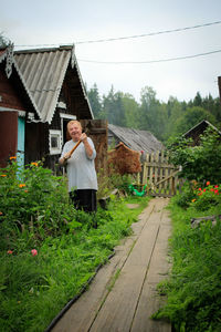 Woman standing by house against building