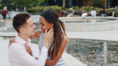 Side view of couple romancing while sitting in park