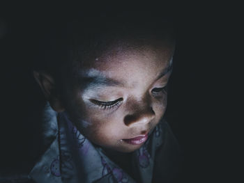 Close-up portrait of mid adult woman against black background